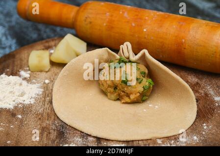 Vorbereitung von Aloo Paratha oder roti parantha chapati Punjab, Nordindien. Weibliche Hand Rollen Vollkornteig Kartoffelpüree mit Rollen Stockfoto