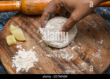 Vorbereitung von Aloo Paratha oder roti parantha chapati Punjab, Nordindien. Weibliche Hand Rollen Vollkornteig Kartoffelpüree mit Rollen Stockfoto