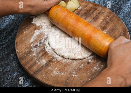 Vorbereitung von Aloo Paratha oder roti parantha chapati Punjab, Nordindien. Weibliche Hand Rollen Vollkornteig Kartoffelpüree mit Rollen Stockfoto