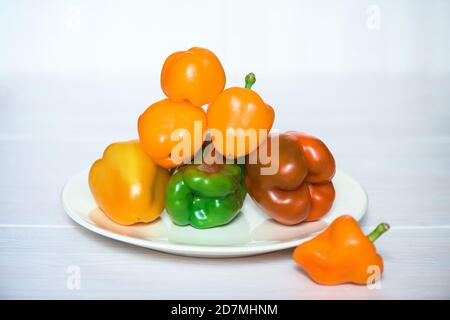 Pyramidenpfeffer rot, orange und grün auf einem Teller auf weißem Hintergrund Stockfoto