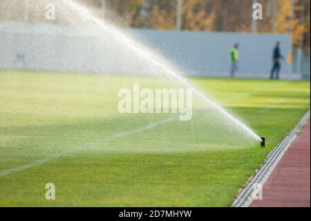 Bewässerungsrasen. Sprinkler bewässern Fußballplatz. System arbeitet auf frischem grünen Rasen auf Fußball oder Fußballstadion. Stockfoto