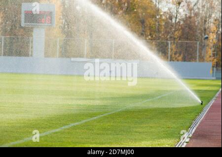 Bewässerungsrasen. Sprinkler bewässern Fußballplatz. System arbeitet auf frischem grünen Rasen auf Fußball oder Fußballstadion. Stockfoto