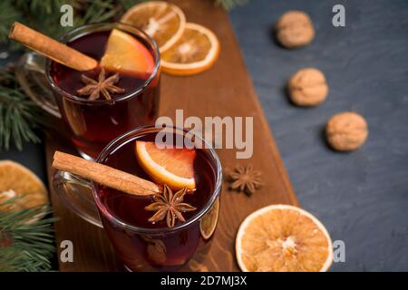 Weihnachtlicher Glühwein in zwei Gläsern mit Orangenscheiben auf Basis von Rotwein mit würzigen Zimtstangen, Sternanis, auf schwarzem Hintergrund. Das vi Stockfoto
