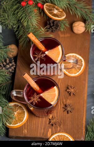 Weihnachtlicher Rotwein Glühwein mit duftenden Gewürzen und Zitrusfrüchten auf einem Holztisch, Nahaufnahme. Traditionelles Heißgetränk zu Weihnachten Stockfoto