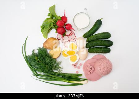 Zutaten für das Rezept der hausgemachten russischen nationalen kalten Okroschka-Suppe auf einem hellen Hintergrund. Kartoffeln, Radieschen, Wurst, Zwiebeln, Kräuter, Eier. Die Stockfoto