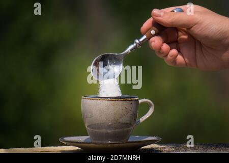 Nahaufnahme eines Teelöffels Zucker in ein gegossen tasse heißen schwarzen Kaffee Stockfoto