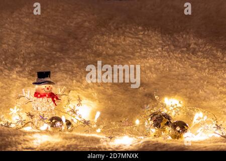 Shiny weihnachten Schneemann mit schwarzem Hut und rotem Schal ist Beleuchtet auf Schneehintergrund durch helle Lichterketten als beleuchtet Weihnachtsdekoration Stockfoto