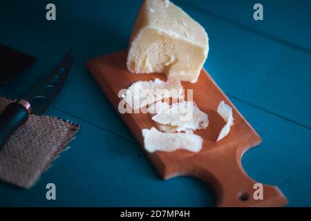 Komponierte Cloesup Detailansicht von gealtertem Cheddar-Käse mit Käsemesser-Set, über vintage blauen Holzhintergrund Stockfoto