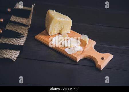 Komponierte Nahaufnahme Detailansicht von gealtertem Cheddar-Käse mit Käsemesser-Set, über vintage brauner Holzkulisse Stockfoto