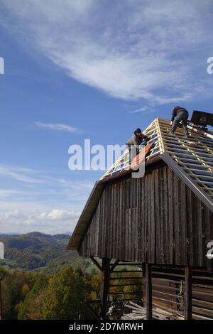 Dachauftragnehmer bei der Neulackung des Dachs auf dem Stall Stockfoto