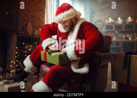 Bad Drunk Santa claus öffnet Geschenke, Humor Stockfoto