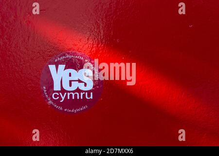 Ein YesCymru Aufkleber zur Unterstützung der Welsh Independence for Wales Auf einem roten Hintergrund Stockfoto