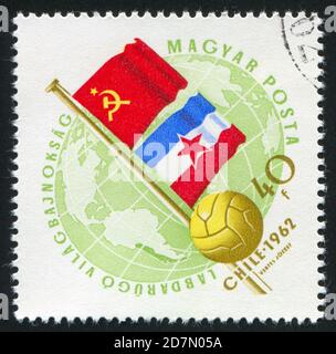 UNGARN – UM 1962: Stempel gedruckt von Ungarn, zeigt Flaggen der UdSSR und Jugoslawiens und Soccerball, um 1962 Stockfoto