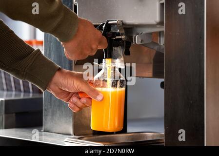 Im Supermarkt füllt man eine Plastikflasche mit frischem Orangensaft. Frischer Orangensaft im Supermarkt. Stockfoto