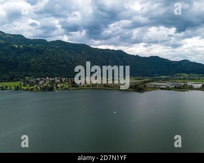 Luftaufnahme auf Steindorf und die oberen Enden des Ossiacher Sees in Kärnten, Österreich mit seinen Mooren und Sümpfen an einem Sommertag mit großer Wolkenlandschaft Stockfoto