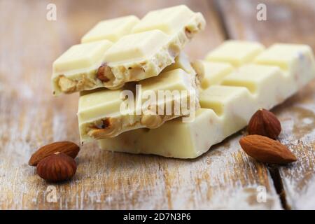 Wenige weiße Schokoladenstücke mit ganzen Haselnüssen und Mandeln Rustikale Holzoberfläche Stockfoto