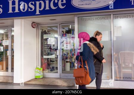 Social Distancing/ High Street/ Charity Konzept - zwei Frauen, die vor dem St Lukes Hospice Charity Shop, Basildon, Essex, Großbritannien, an einander hergehen Stockfoto