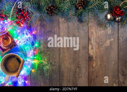 Weihnachten oder Neujahr Grußkarte mit Platz für Text. Helle Weihnachtslichter, Kiefernnadeln, Dekorationen auf einem dunklen rustikalen Holzhintergrund. Frohe Stockfoto