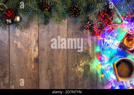 Weihnachten oder Neujahr Grußkarte mit Platz für Text. Helle Weihnachtslichter, Kiefernnadeln, Dekorationen auf einem dunklen rustikalen Holzhintergrund. Frohe Stockfoto