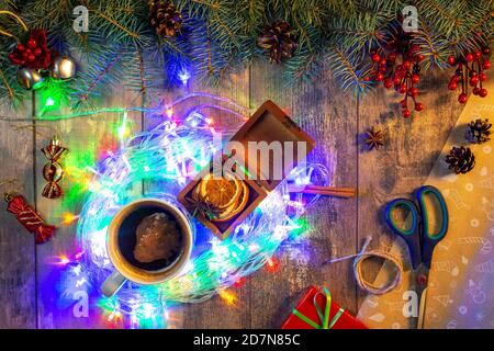 Konzept der Vorbereitung auf Weihnachtsferien. Weihnachtliche Zusammensetzung Fichtenzweige, Schere, Geschenkpapier, helle Weihnachtslichter. Stockfoto