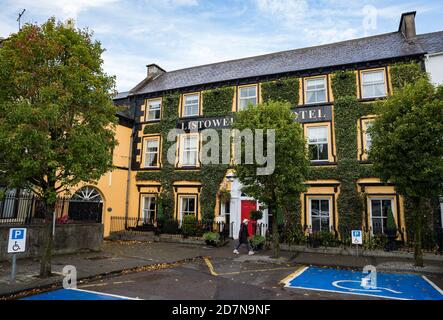 Listowel, Irland - 24. Oktober 2020: Frau in Gesichtsmaske, die an einem geschlossenen Hotel in der Stadt Listowel wegen der Cover-19-Pandemie vorbeigeht Stockfoto