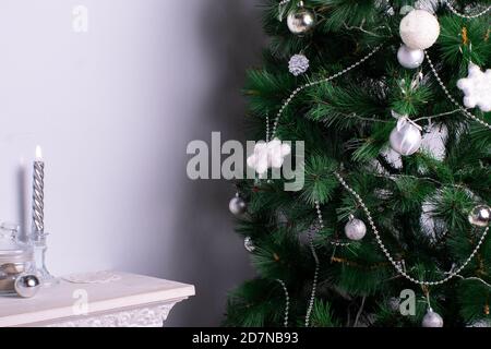 Fest der Geburt Christi. Wunderschön dekorierter Weihnachtsbaum mit weißen Kugeln und silbernen Schneeflocken Stockfoto