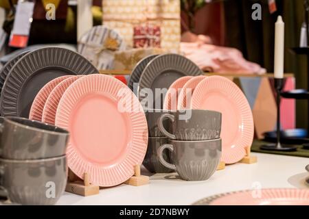 Neue graue, rosa Tischeinstellung. Moderner Stil. Dient für den Shop-Katalog. Heiße Getränke, Tee oder Kaffee. Stilvolle, elegante Keramikgeschirr auf den Regalen Stockfoto