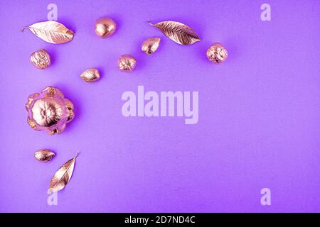 Kürbisse, Nüsse und Blätter in kupferfarbener Farbe auf violettem Hintergrund. Flaches Layout mit Platz für Text. Hochwertige Fotos Stockfoto