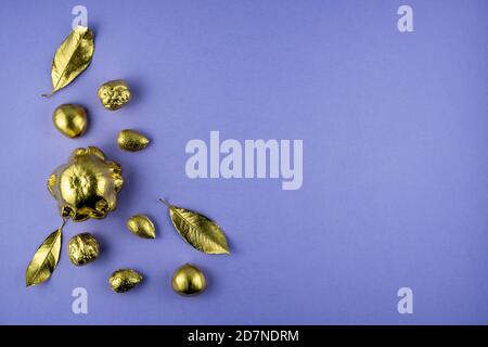 Kürbisse, Nüsse und Blätter in Gold auf violettem Hintergrund gemalt. Flaches Layout mit Platz für Text. Hochwertige Fotos Stockfoto