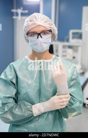 Junge professionelle Chirurg in schützende Arbeitskleidung im Operationssaal stehen Stockfoto