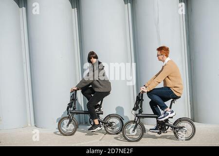 Junger Mann und Frau fahren eBikes, Blick auf einander. An einem sonnigen Herbsttag Stockfoto