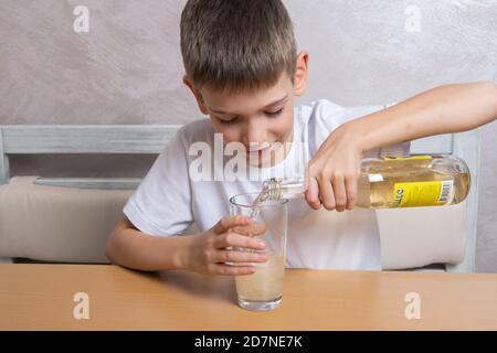 Ein süßer Junge gießt russisches Mineralwasser Duchesse aus einer Glasflasche in ein Glas, 10.15.2020, Russland Stockfoto