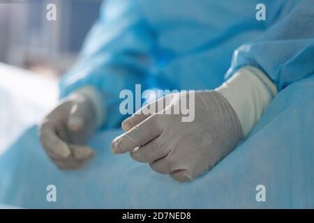 Handschuhen des müden professionellen Chirurgen, der im Operationssaal sitzt In der Pause Stockfoto