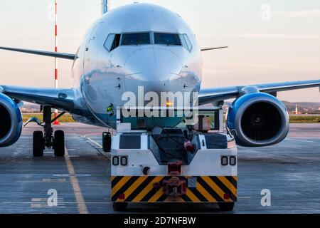 Der Schlepper schiebt das Passagierflugzeug auf das Flughafenvorfeld Stockfoto