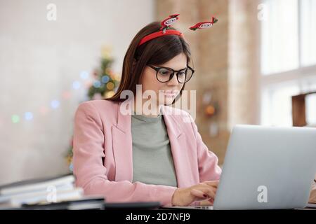 Junge ziemlich seriöse Manager Networking gegen dekoriert Firtree im Büro Stockfoto