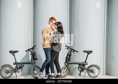 Glückliches Paar, das neben eBikes tanzt und eine gute Zeit hat. An einem sonnigen Herbsttag Stockfoto