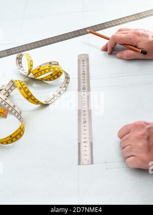 Schneiderhände , Maßband, Lineale und Bleistift auf Muster Layout Kleid auf Graphenpapier zu Hause gezeichnet Stockfoto