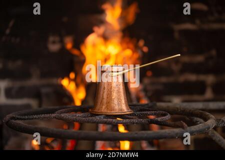 Brauen Sie Kaffee in einem Türke auf einem offenen Feuer. Das Konzept einer gemütlichen Atmosphäre und Getränke. Stockfoto