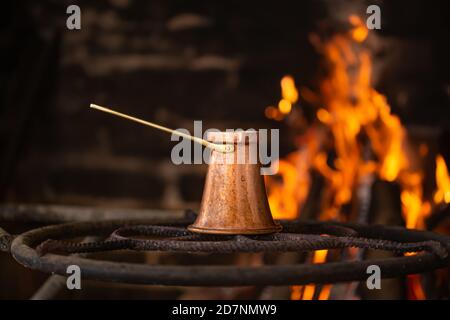 Brauen Sie Kaffee in einem Türke auf einem offenen Feuer. Das Konzept einer gemütlichen Atmosphäre und Getränke. Stockfoto