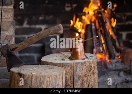 Brauen Sie Kaffee in einem Türke auf einem offenen Feuer. Das Konzept einer gemütlichen Atmosphäre und Getränke. Stockfoto