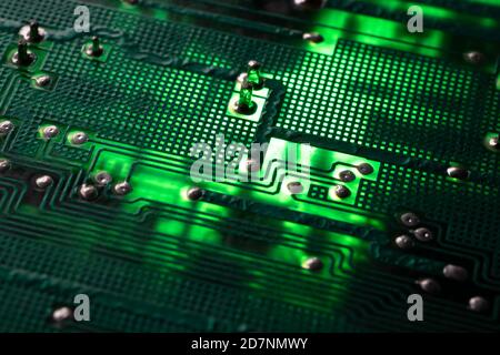 Beleuchtete, frische grüne Elektronikplatine mit vielen elektrischen Komponenten. Enge Schärfentiefe Stockfoto