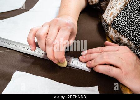 Weibliche Hand zeichnet Muster des Kleides auf braunem Stoff durch Seife aus nächster Nähe zu Hause Stockfoto