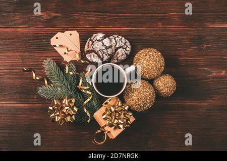 Weihnachtskomposition mit Tasse Kaffee, Schokoladenkekse, Fichtenzweig und Geschenkbox auf braunem dunklen Tisch, Draufsicht. Stockfoto