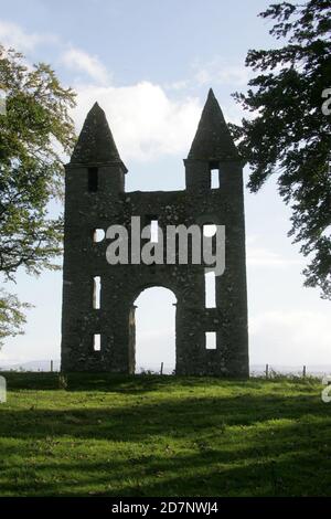 Grenzt an den Hunty Mundy im Mellerstain House bei Kelso. Hundy Mundy Tower, Tower in Melrose, Schottland, Großbritannien. Eine Torheit, die nach einer Prinzessin benannt wurde, die Körper in einer natürlichen Waldbestattung überblickt.Eine gotische Torheit, die zur Vervollständigung der entworfenen aussicht, die sich südöstlich von Mellerstain in den schottischen Grenzen erstreckt, gebaut wurde, befindet sich Hundy Mundy in einer spektakulären Lage, eine Meile (1,5 km) nordöstlich von Smailholm und 5 Meilen (8 km) Nordwestlich von Kelso. Es wurde 1726 begonnen und besteht aus einem hohen Torbogen zwischen quadratischen Türmen, die von Pyramiden bedeckt sind, und war das Werk von William Adam (1689 - 1748), der der Architekt gewesen war Stockfoto