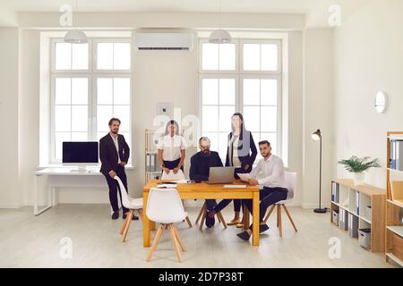 Ein Team von Geschäftsleuten diskutiert Geschäftsideen und lächelt an der Kamera im Büro. Stockfoto