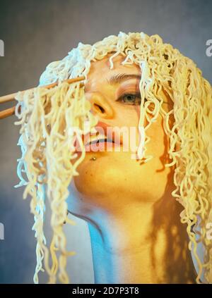 Lustige hungrige Mädchen mit lockigen Nudeln auf dem Kopf. Stockfoto