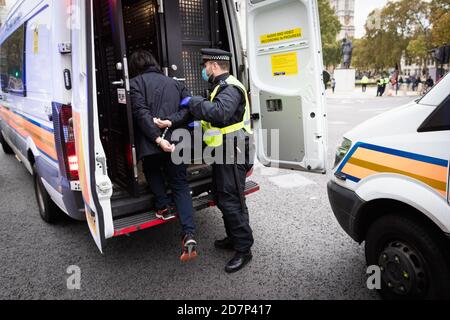 London, Großbritannien. Okt. 2020. Ein Mann wird verhaftet und in den Rücken eines Polizeiwagens vor das Parlamentsgebäude geführt. Die Bewegung Unite for Freedom organisierte einen Protest unter dem Banner "Wir haben die Macht", um den Kräften zu zeigen, dass sie sich nicht mit dem einverstanden erklären, was sie als ungesetzliche Sperre ansehen. Kredit: Andy Barton/Alamy Live Nachrichten Stockfoto