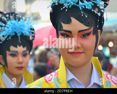 Kostümierte weibliche Thai-chinesische Performerinnen mit gemalten traditionellen Peking-Oper Gesichtsmasken posieren für die Kamera bei bunten chinesischen Neujahr Straßenparade. Stockfoto