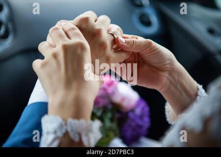 Junge Braut legte einen goldenen Ehering auf den Finger des Bräutigams, Nahaufnahme. Stockfoto