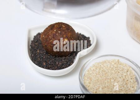 Getrocknete Früchte und Nüsse Süßigkeiten. Während der Epidemie zu Hause in Isolation gemacht. Liegt auf schwarzen Sesamsamen. Stockfoto